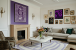 Living room with a fireplace, sofa, purple rug, and decorative wall art.