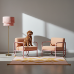 Two blush pink armchairs with metal frames are arranged in a modern room with a dog sitting on the left chair. A matching pink floor lamp stands on the left, and a geometric pink and gold rug is on the floor.