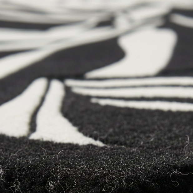 Close-up of a black and white abstract patterned rug showing the textured pile and contrasting fibers.