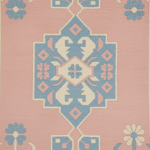 A close-up of a patterned rug featuring a central blue and cream geometric medallion on a dusty pink background, with blue and cream floral motifs in the corners.