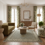 A beautifully styled living room featuring a large traditional patterned area rug in muted green and beige tones, paired with a green tufted sofa, a light wood coffee table, and matching floral curtains.