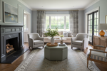 Living room with gray rug, armchairs, coffee table, and fireplace.