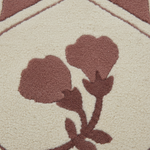 Close-up of a textured area rug featuring a cream-colored background with a stylized floral motif in a muted terracotta brown.