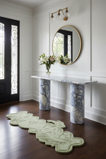 Foyer with marble console table, round mirror, and decorative rug.