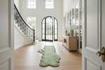 Green horse rug on a wooden floor in a bright, modern home interior with white walls and large windows.
