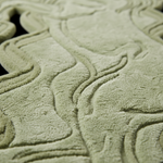 Close-up of a textured fabric surface in a muted sage green color, showing a wavy, embossed pattern and soft plush material.