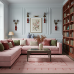 A styled living room featuring a large pink sectional sofa with green and cream accent pillows, a wooden coffee table, a pink patterned rug, and a tall wooden bookshelf filled with books.