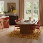 Dining room with a round wooden table, red chairs, and a yellow rug.