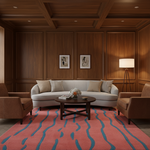 A styled living room interior featuring a curved light gray sofa with beige and striped pillows, flanked by two brown armchairs on a pink and blue patterned rug. The room has dark wood paneling on the walls and ceiling, a dark wood coffee table, and a floor lamp.