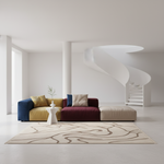 A modern modular sectional sofa in blue, mustard yellow, burgundy, and beige, styled in a minimalist white room with a spiral staircase, a patterned area rug, and a small white side table.