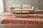 Beige sofa with a red floral rug and gold coffee table in a room with white walls and wooden flooring.