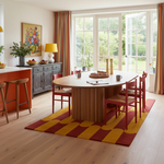 Dining room with a round wooden table, red chairs, and a colorful yellow and red rug.