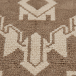 Close-up of a woven rug with a geometric pattern in taupe brown and cream.