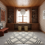 A styled home office or study featuring a large cream and dark gray geometric area rug on a gray carpet, set in a room with wood-paneled ceilings, built-in wooden shelving, chevron wallpaper, and a window with sheer curtains.
