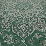 A close-up of a green and gray patterned rug with a traditional medallion design.