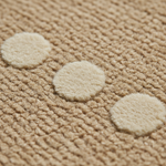 Close-up of a textured beige woven rug with three large off-white circular spots arranged diagonally.