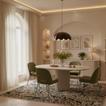 A modern dining room featuring a round white pedestal table surrounded by four olive green upholstered chairs. A dark brown lotus-shaped pendant light hangs over the table, which sits on a blue and beige patterned area rug.