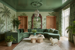 Luxurious living room with green walls, a curved green sofa, and decorative gray rug.