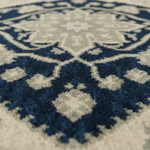 Close-up of a plush shag rug with a traditional medallion pattern in navy blue and cream.