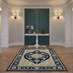 A large traditional area rug with a navy blue and cream floral pattern is displayed on a herringbone wood floor in a beautifully decorated entryway with teal doors and wall sconces.