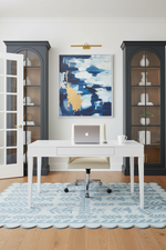 Home office with a white desk, laptop, scallop blue rug, and decor elements.