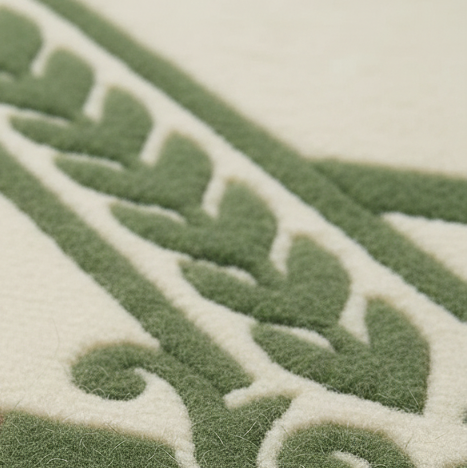 Close-up of a textured woven fabric with a repeating leaf or vine pattern in muted green on an off-white background.