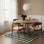 Dining room with wooden table and chairs on a striped scalloped rug