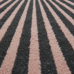 Close-up of a shaggy rug with alternating vertical stripes in dark charcoal gray and dusty pink, shown in perspective.