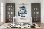 Modern home office with a desk, abstract black and white rug, and decorative items.