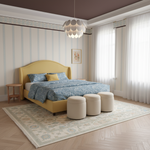 A styled bedroom interior featuring a mustard yellow upholstered bed with blue patterned bedding, a matching yellow headboard, three cream ottomans at the foot of the bed, a large patterned area rug, striped wallpaper, sheer curtains, and a modern pendant light.