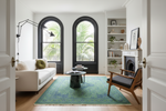 Living room with a green rug, white sofa, and wooden chair.
