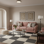 A styled living room featuring a dusty pink sofa with neutral throw pillows, set on a large black and white checkered rug. The room has warm beige walls, two framed abstract prints, a white round coffee table, and a black floor lamp.
