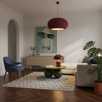 A modern living room interior with a large burgundy pleated pendant light hanging over a beige sofa, a blue armchair, a patterned rug, and a framed art print on the wall.