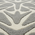 Close-up of a plush area rug with a raised geometric pattern in light gray and off-white.