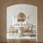 Dining room with a round table and chairs, gray handmade rug, featuring a textured wall and pendant light.