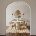 Dining room with a round table, geometric rug, chairs, and decorative elements.