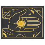 A rectangular black rug with a minimalist gold line-art design featuring a hand holding a sunburst, leaves, and abstract shapes, shown flat against a white background.