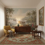 A styled interior room featuring a large vintage-style tropical mural wallpaper on the back wall, depicting palm trees, ships on the water, and figures by the shore. The room includes a mustard yellow armchair, a mid-century modern wooden sideboard with a lamp, a small round wooden table, a patterned area rug, and a matching framed wall mirror.