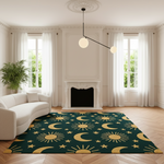 A dark teal green area rug with a gold celestial pattern of crescent moons, stars, and suns, styled in a bright, modern living room with a white sofa and wood floors.