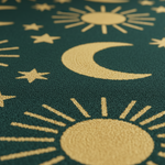 Close-up of a dark teal textured surface with a repeating pattern of gold celestial motifs, including crescent moons, stars, and suns.