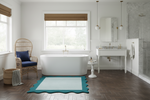 Modern bathroom with freestanding bathtub, scallop rug, sink, and chair.