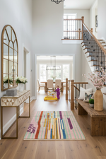 Modern home interior with a child playing on a colorful rug, surrounded by furniture and decor.