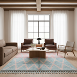 A styled living room interior featuring a large light blue and pink geometric patterned area rug with fringe, surrounded by a beige sofa, two brown armchairs, a wooden coffee table, and white sheer curtains.