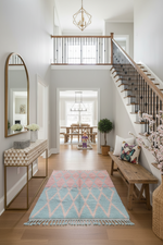 Modern interior with a staircase, blue and pink shaggy rug, and decorative items.