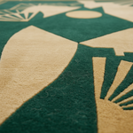 Close-up of a textured area rug with a modern geometric design in dark green and beige, showing the pile texture and fine details.