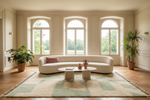 Modern living room with a curved sofa, green shaggy rug, coffee table, and large windows.