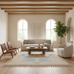 A styled living room interior with a cream sofa, two wooden chairs, a round white accent chair, a low wooden coffee table, a large patterned area rug, arched windows, and a potted plant.