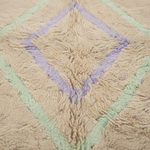 Close-up of a textured shag rug with a diamond pattern in beige, light green, and lavender purple.