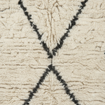 Close-up of a textured cream-colored rug with a black geometric line pattern.