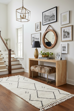 Staircase with wooden console table, runner rug, mirror, and decor items in a home setting.